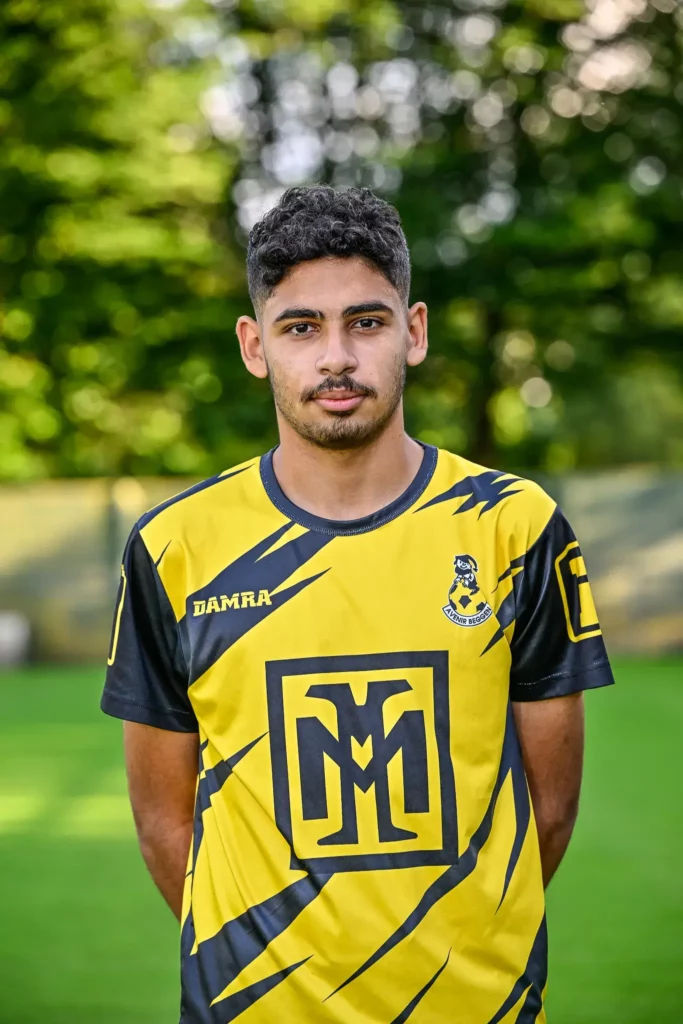 A player from the first team in his kit, posing on the pitch