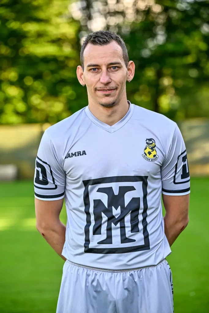 A player from the first team in his kit, posing on the pitch