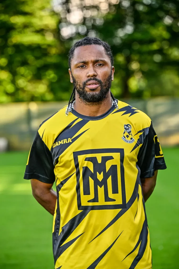 A player from the first team in his kit, posing on the pitch