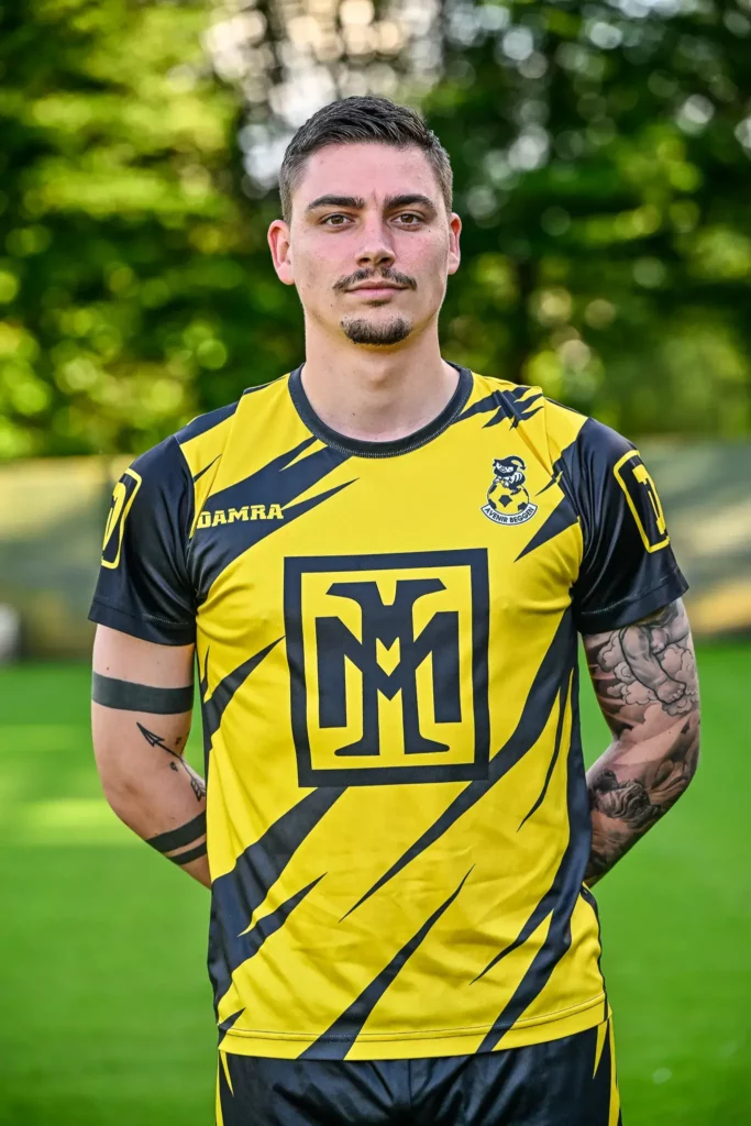 A player from the first team in his kit, posing on the pitch