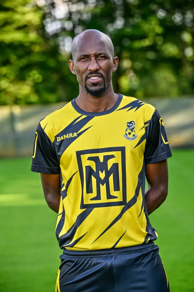 A player from the first team in his kit, posing on the pitch