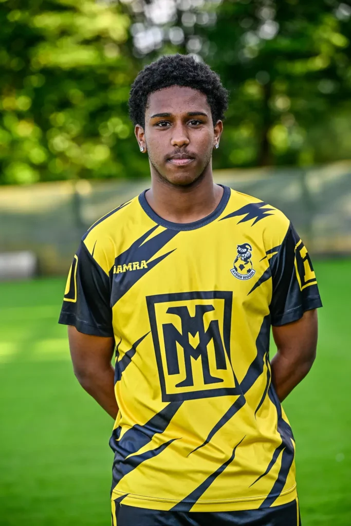 A player from the first team in his kit, posing on the pitch