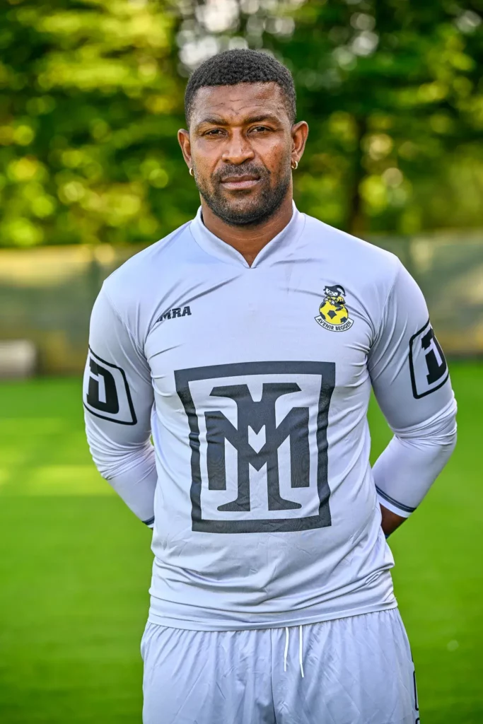 A player from the first team in his kit, posing on the pitch