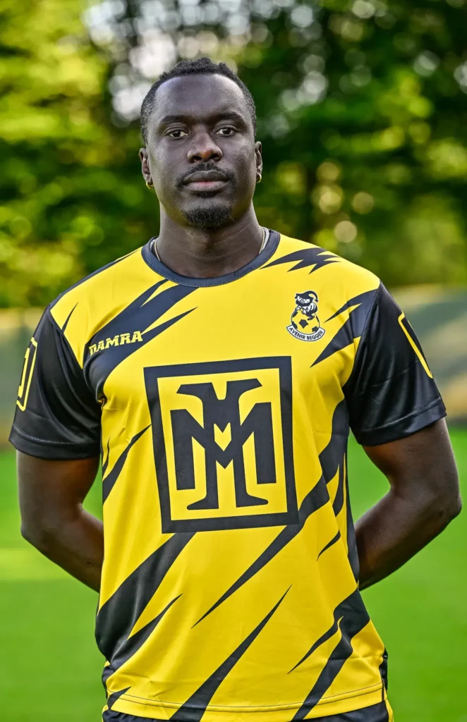 A player from the first team in his kit, posing on the pitch