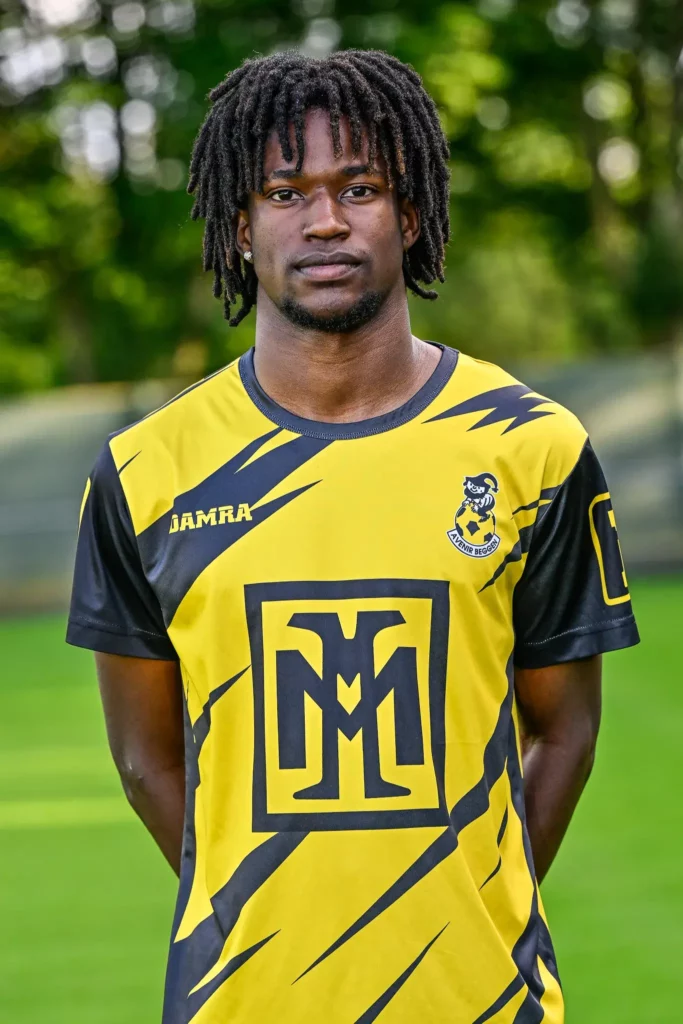 A player from the first team in his kit, posing on the pitch