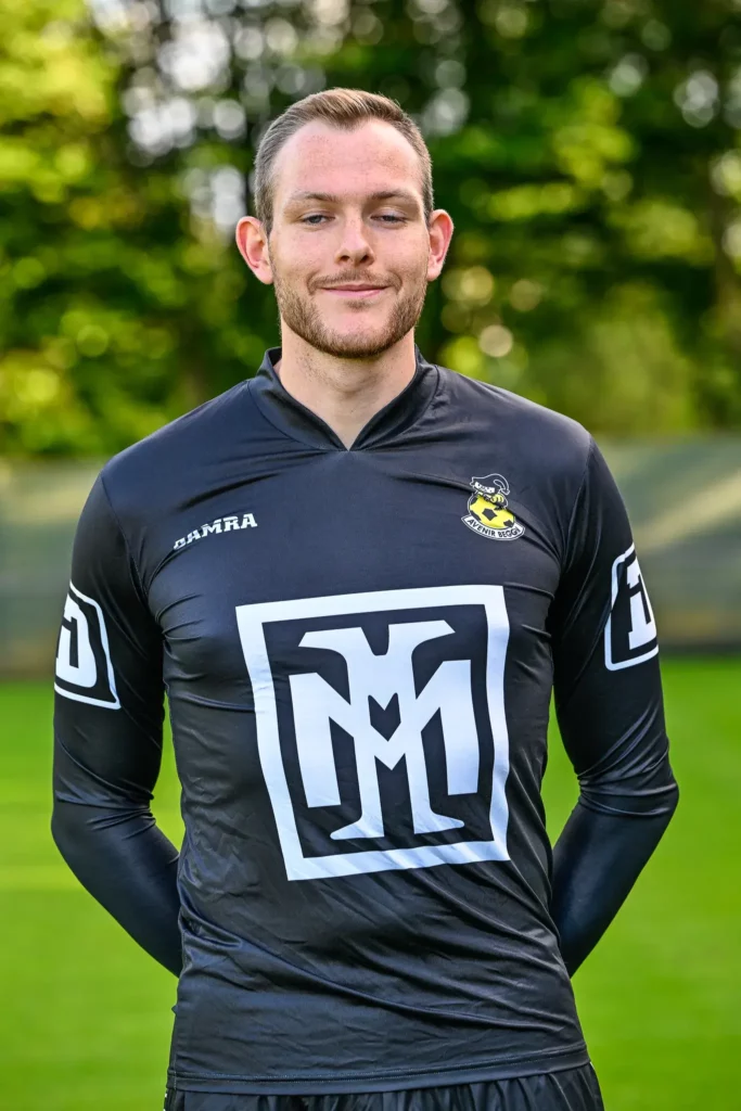 A player from the first team in his kit, posing on the pitch