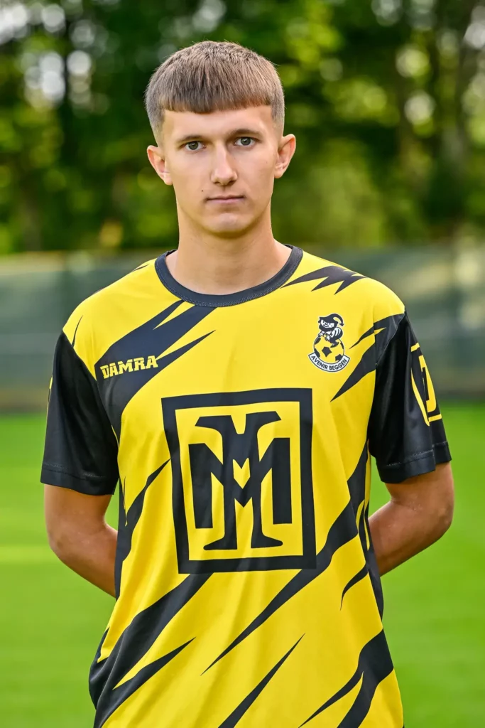 A player from the first team in his kit, posing on the pitch