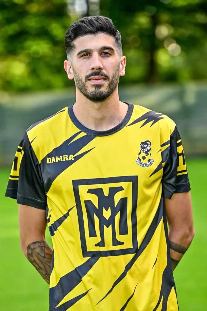 A player from the first team in his kit, posing on the pitch