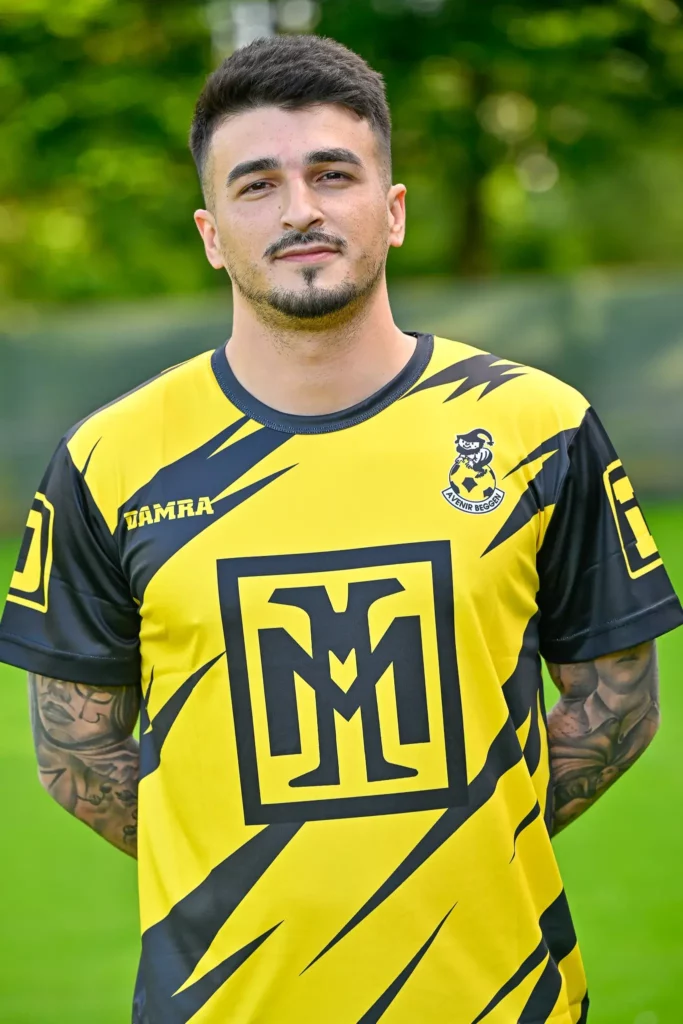 A player from the first team in his kit, posing on the pitch