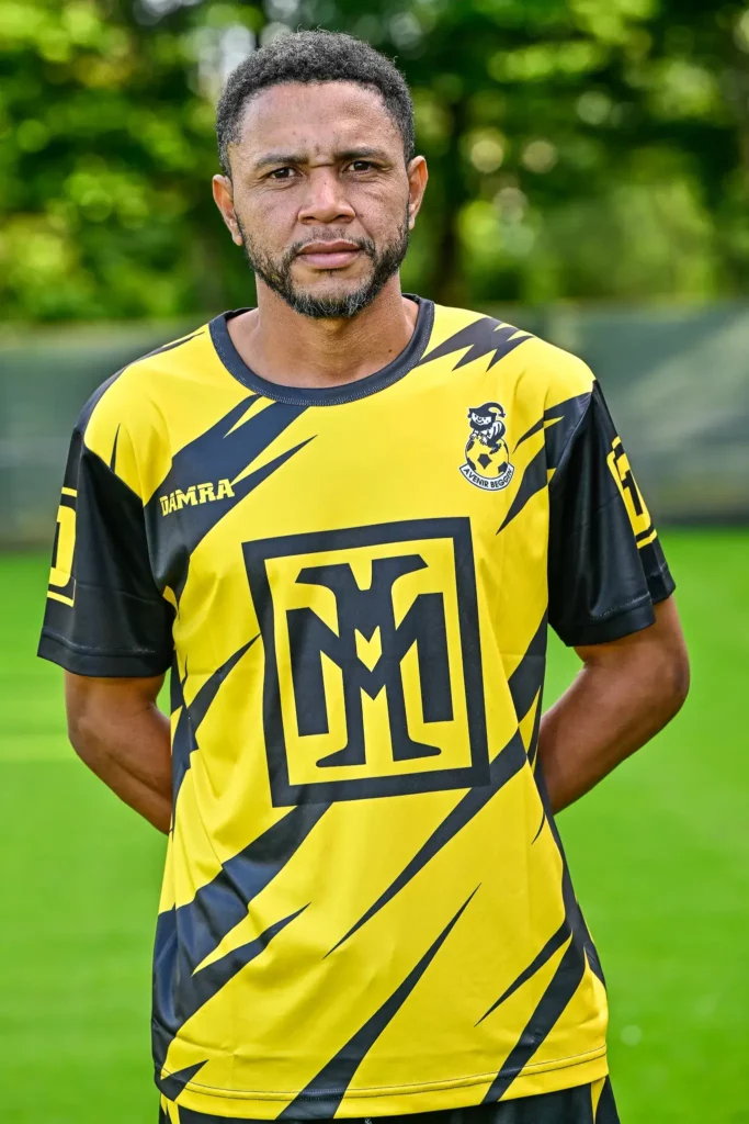 A player from the first team in his kit, posing on the pitch