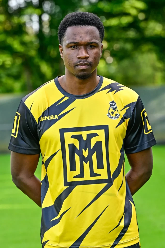 A player from the first team in his kit, posing on the pitch