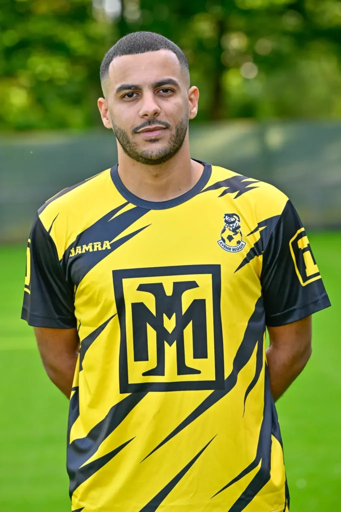 A player from the first team in his kit, posing on the pitch