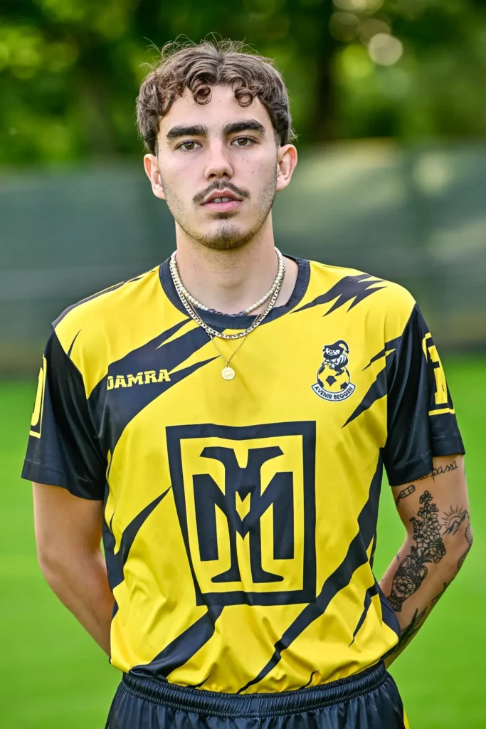 A player from the first team in his kit, posing on the pitch