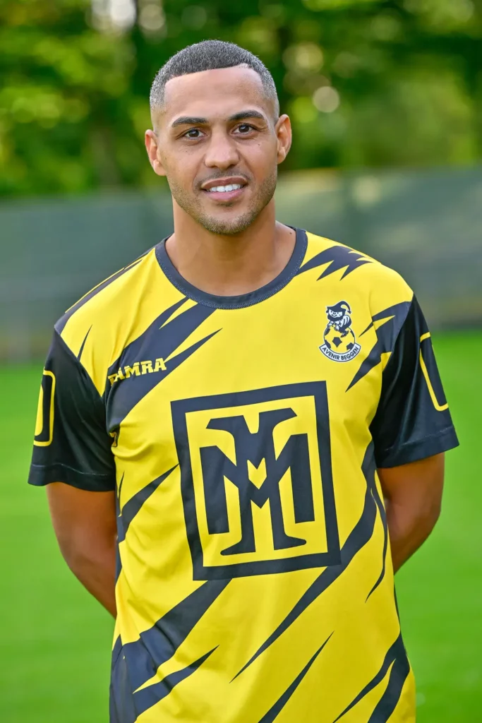 A player from the first team in his kit, posing on the pitch