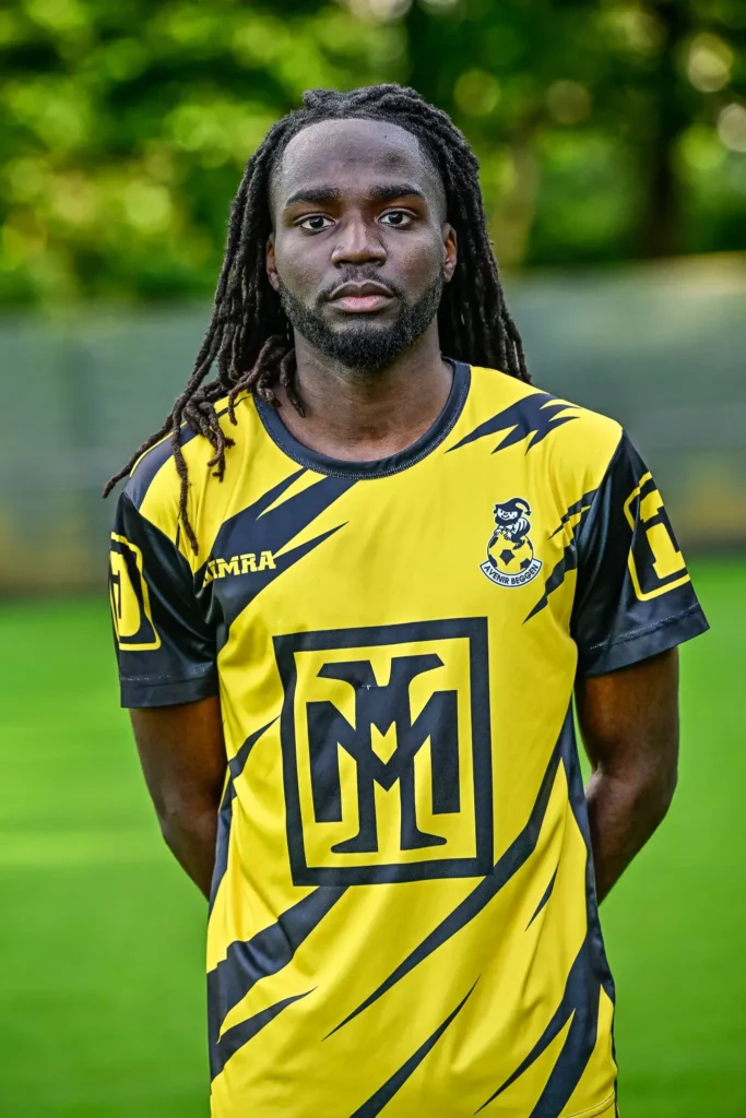 A player from the first team in his kit, posing on the pitch