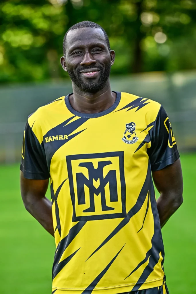 A player from the first team in his kit, posing on the pitch