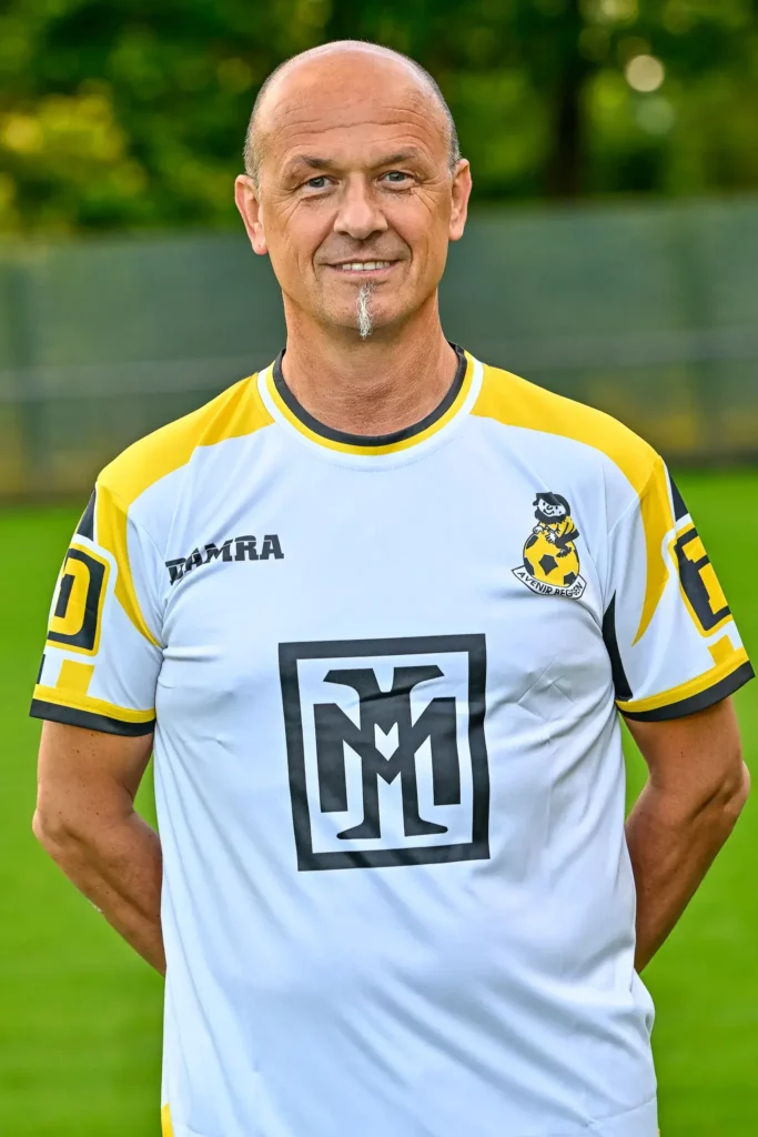 A member from the coaching staff in his kit, posing on the pitch