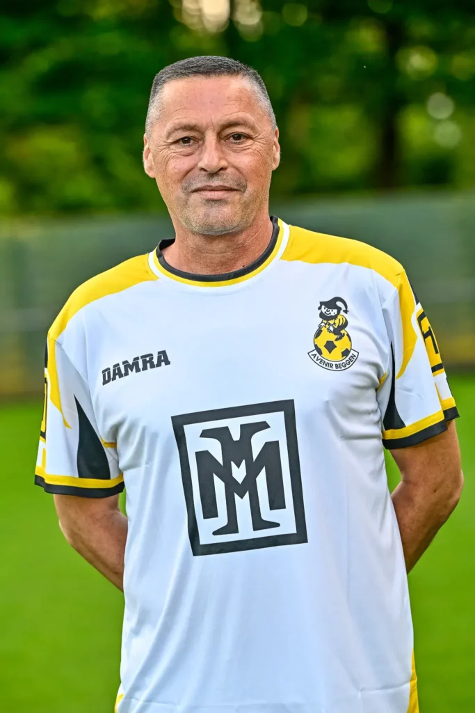 A member from the coaching staff in his kit, posing on the pitch