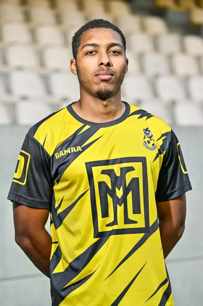 A player from the first team in his kit, posing on the pitch