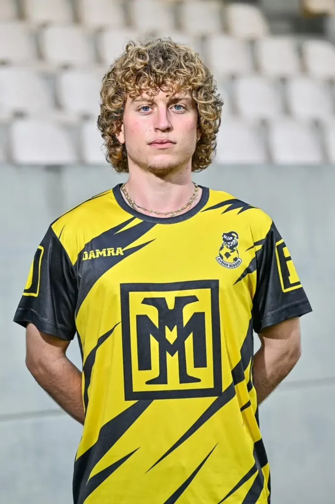 A player from the first team in his kit, posing on the pitch